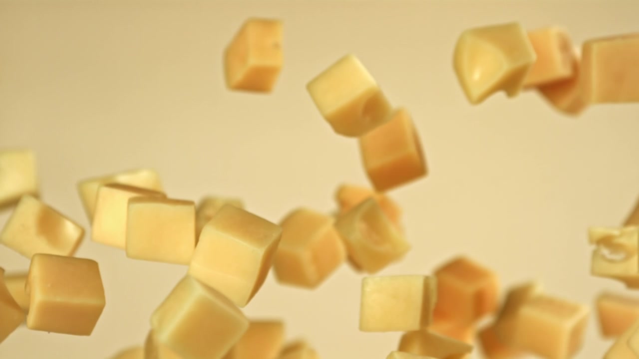 Cubetti di formaggio fresco che cadono e galleggiano al rallentatore