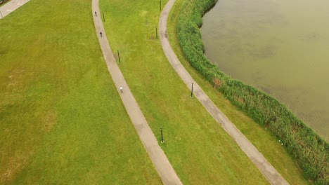 a-bird's-eye-view-over-a-paved-pathway-with-3-people-riding-their-bicycle