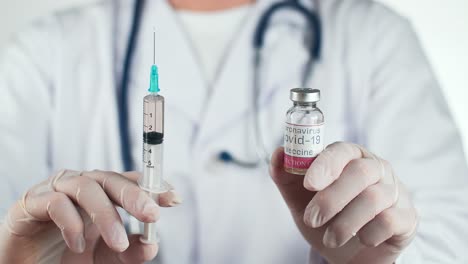doctor holding covid-19 vaccine and syringe