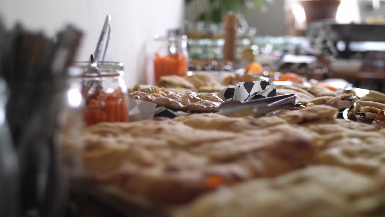 피타와 포카치아 빵이 전경에 놓여 있고 칼붙이 옆에 당근 막대기와 배경에 더 많은 음식이 있는 지중해식 뷔페를 닫습니다.