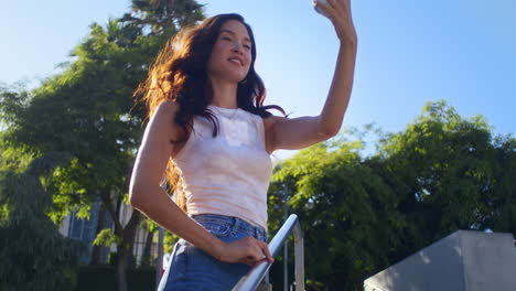 una mujer sonriente fotografiando con su teléfono inteligente. una chica asiática subiendo las escaleras en un parque de la ciudad.