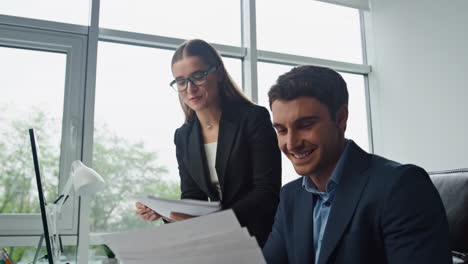 Happy-businesswoman-talking-colleague.-Two-smiling-partners-working-computer