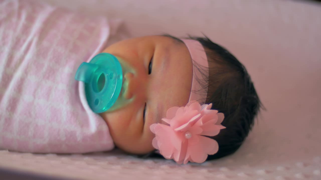 Close up of a newborn baby wrapped in a blanket laying in a crib