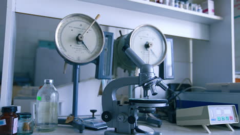 old-fashioned microscope on the table of medical laboratory. tools and appliances on the shelves at backdrop.