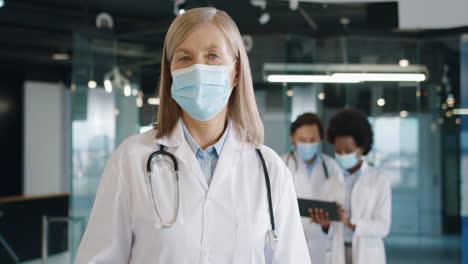 vista de cerca de una doctora caucásica con máscara médica mirando la cámara de pie en el hospital