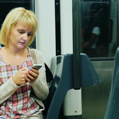 a woman rides in a subway car and uses a smartphone 2