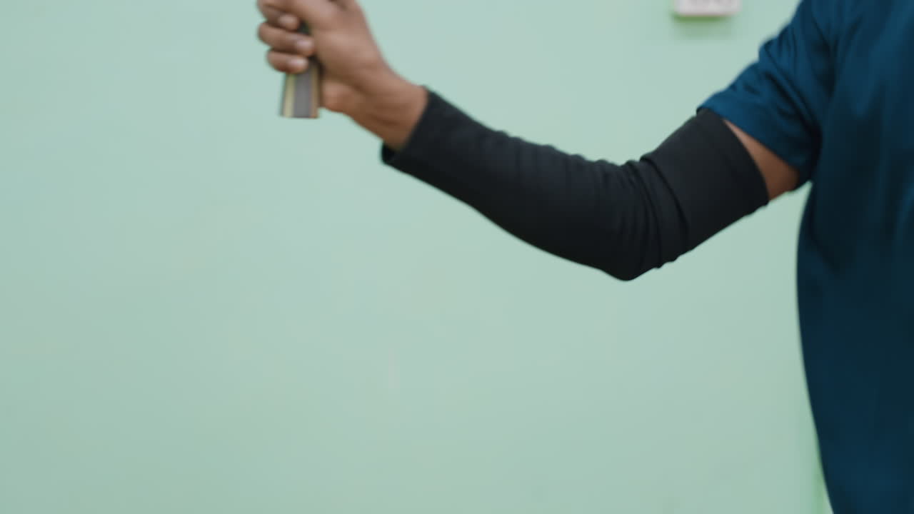 Close up of athlete player in sportswear gripping table tennis paddle during training session against indoor background, focusing on hand movement and concentration for precision practice shot
