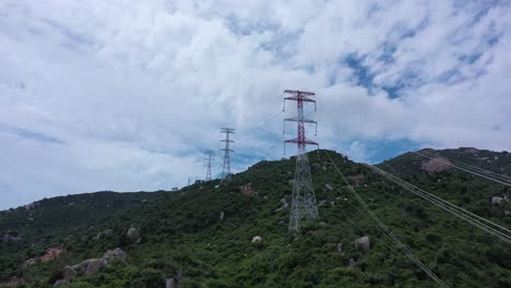 aerial drone footage of high voltage power transmission towers with line pylon in mountainous area to distribute electricity - natural landscape and industrial concept for sustainable development