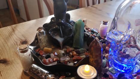 Backflow incense collection of colourful healing crystals and mysterious spiritual skull on wooden kitchen table