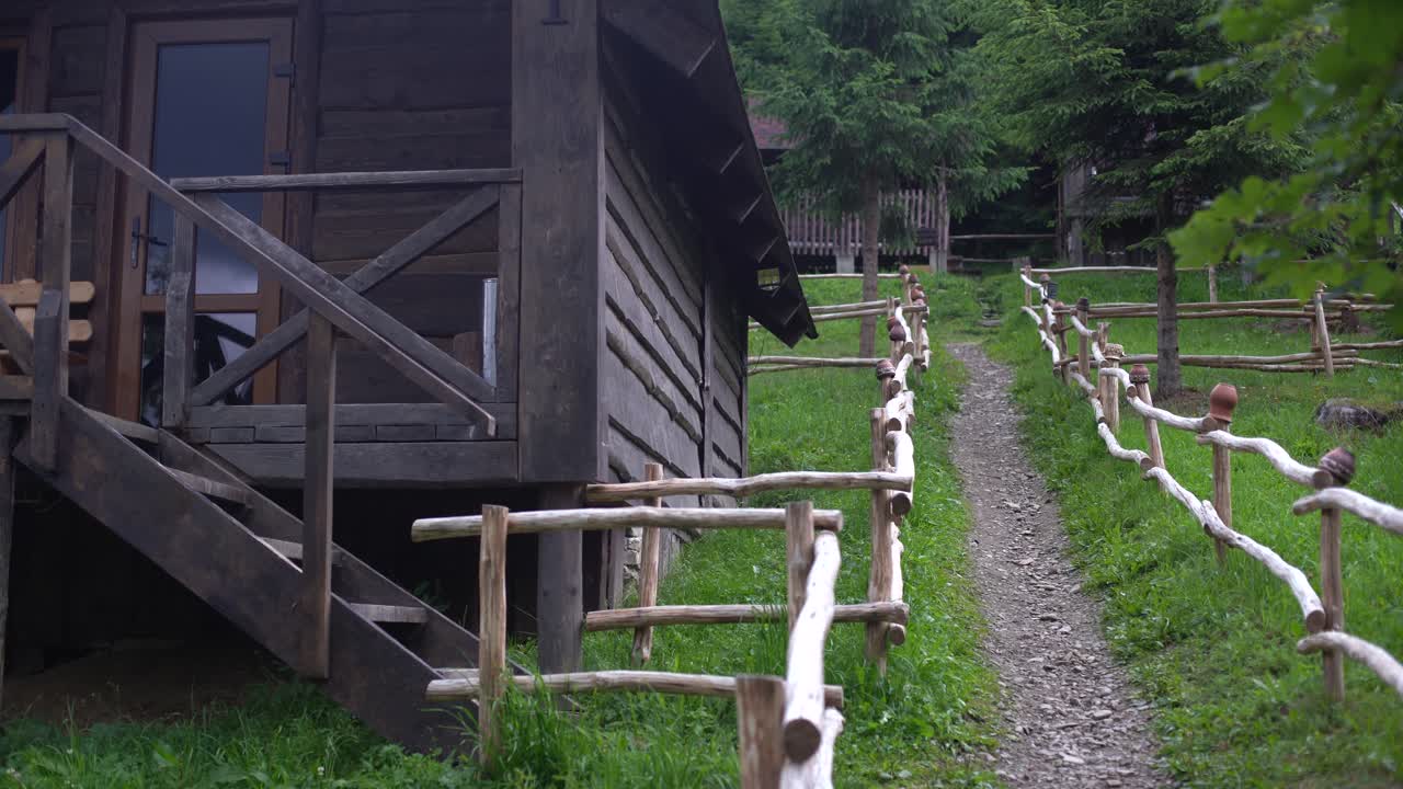 Traditional clay pitcher jug on log in the yard of house with a rustic wooden fence background Old ceramic pot