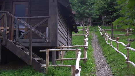 Traditioneller-Tonkrug-Auf-Baumstamm-Im-Hof-Des-Hauses-Mit-Rustikalem-Holzzaun-Im-Hintergrund,-Alter-Keramiktopf