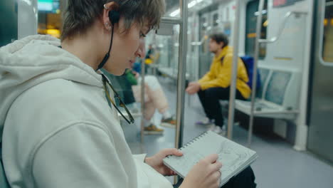 female passenger drawing sketch in train during subway ride