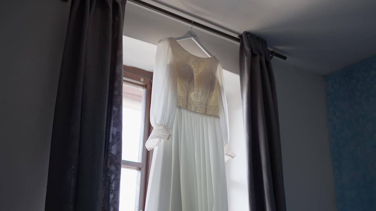 Wedding dress laid out on the window sill, bathed in sunlight, waiting for the ceremony