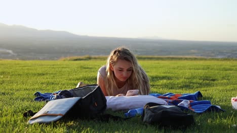 shot of a beautiful young woman laying on a blanket on the grass at a park