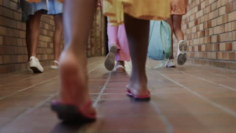 escolares diversas con bolsas escolares caminando en el corredor de la escuela primaria en cámara lenta