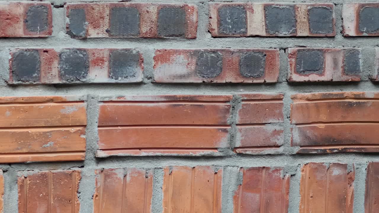 Detailed view of a brick wall showcasing varied textures and colors in a repeating pattern.