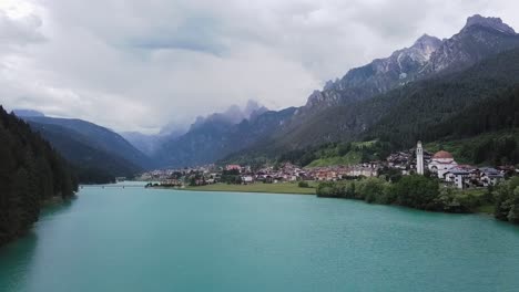 Drone-shot-of-Lago-di-Santa-Caterina-with-the-city-of-Auronzo-in-the-background