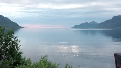 Un-Hombre-Junto-A-Una-Tienda-De-Campaña-En-El-Techo-De-Un-Coche-En-El-Camping-De-Sifjord,-En-Noruega