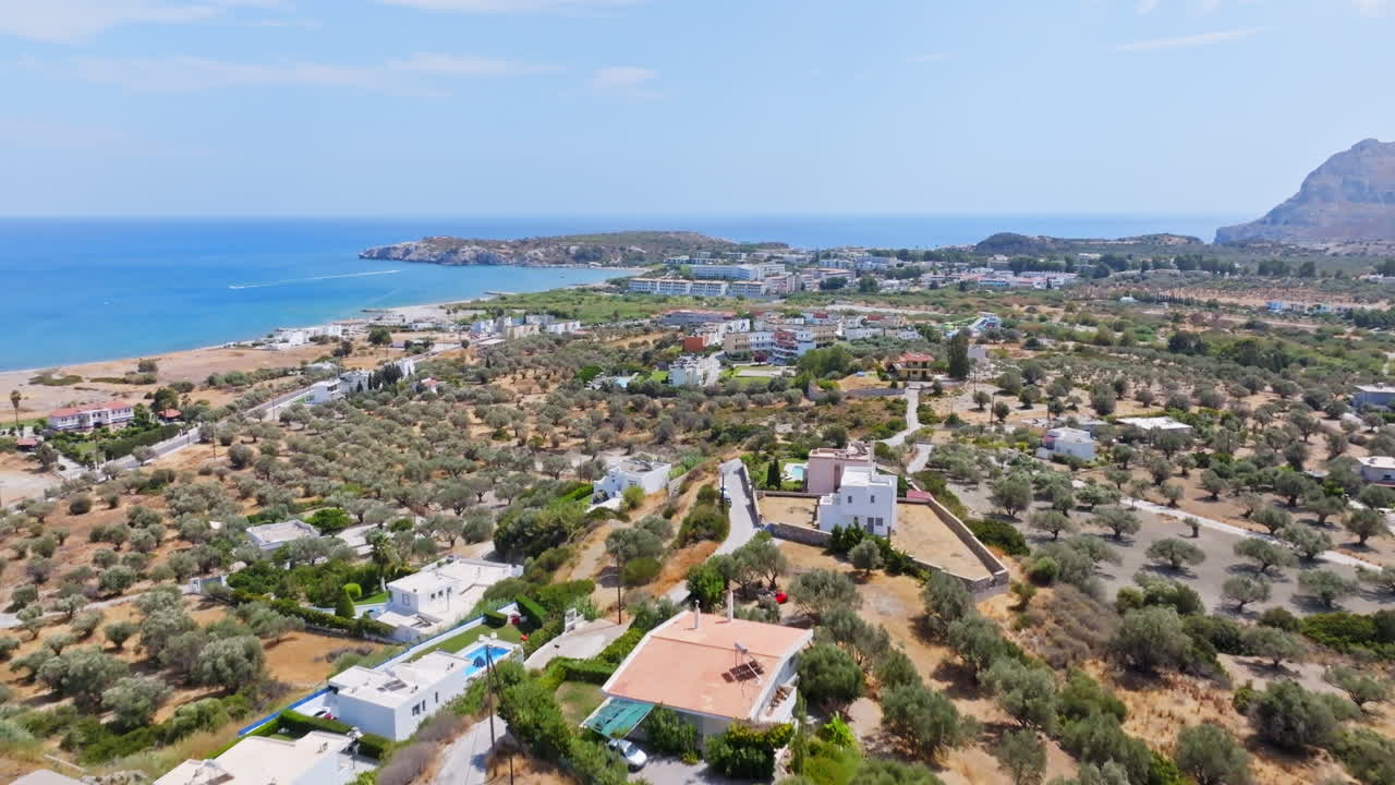 Drone shot over hilltop villas, toward the Kolymbia village, sunny day in Rhodes