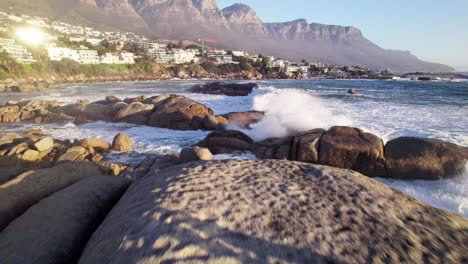 dramatic waves crashing on rocky coast with mountain view
