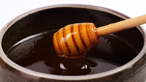 honey dripper is dipped to take honey in a bowl on the white background. honey dripping from honey dripper, healthy organic thick honey closeup, sweet honey dessert 4k. slow motion