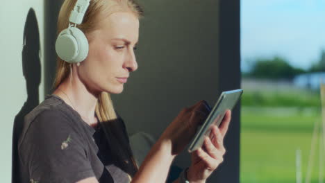 Una-Mujer-Con-Auriculares-Inalámbricos-Utiliza-Una-Tableta-Digital-Mientras-Estudia-En-Línea