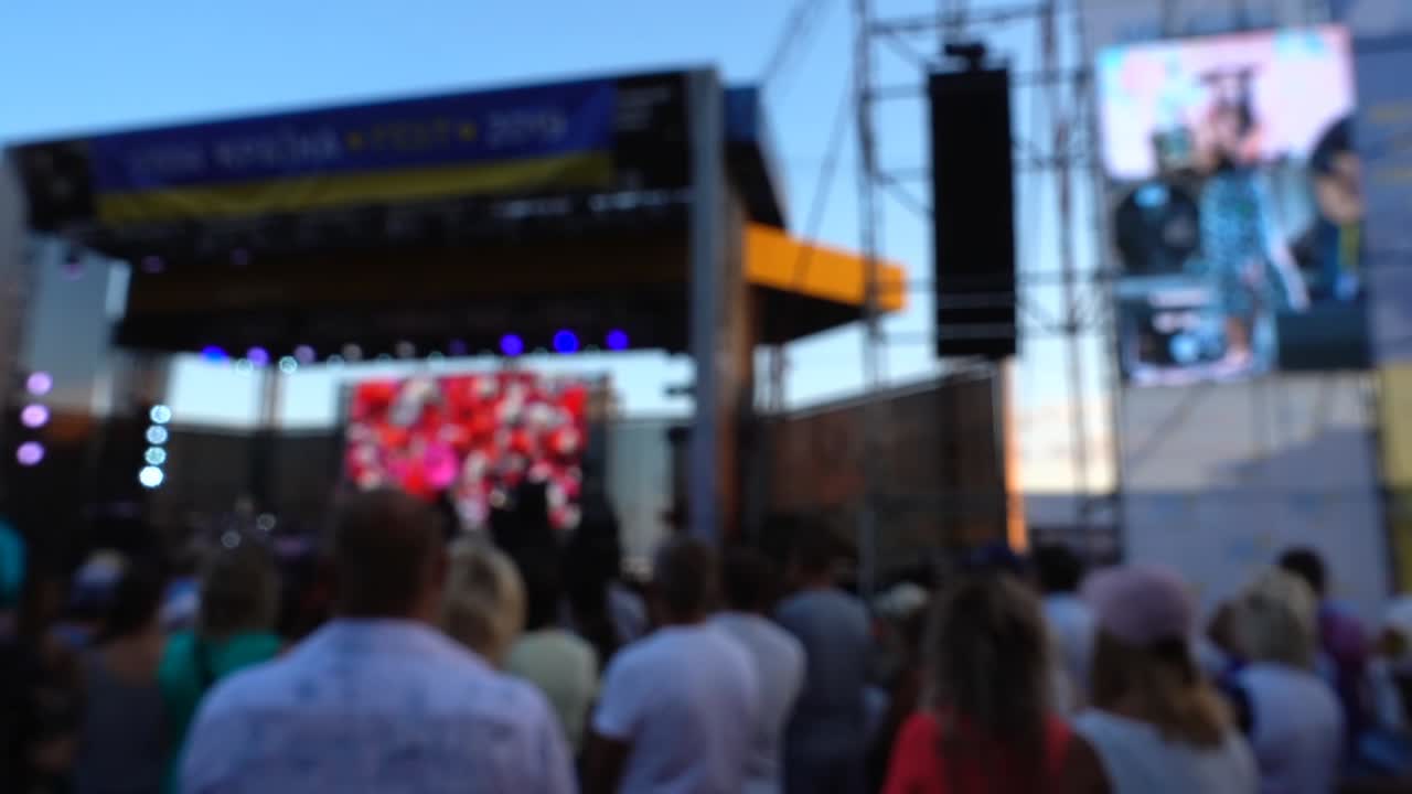 Concerto sul palco. Folla di persone e musicisti sulla scena. Fuori fuoco