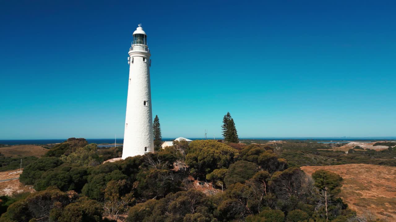 imagen de un dron volando cerca del faro de wadjemup en la isla de rottnest en un día soleado revelando el paisaje en el fondo, australia occidental