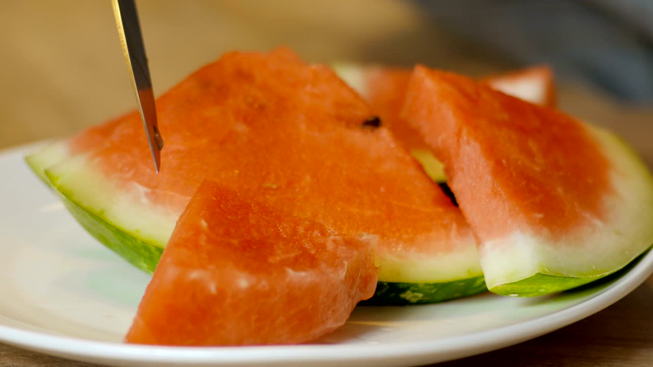 manos cortando sandía