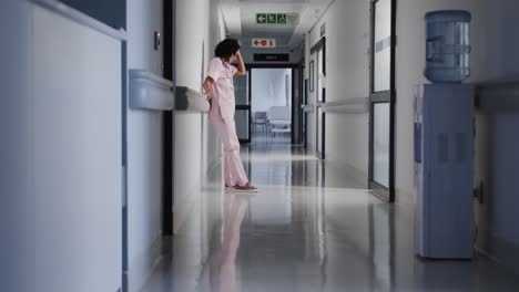 Enfermera-Birracial-Estresada-Apoyada-En-La-Pared-Del-Hospital-En-Cámara-Lenta