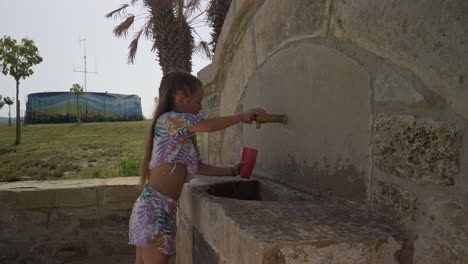 niño joven lava su taza de beber roja antes de tomar bebida de agua