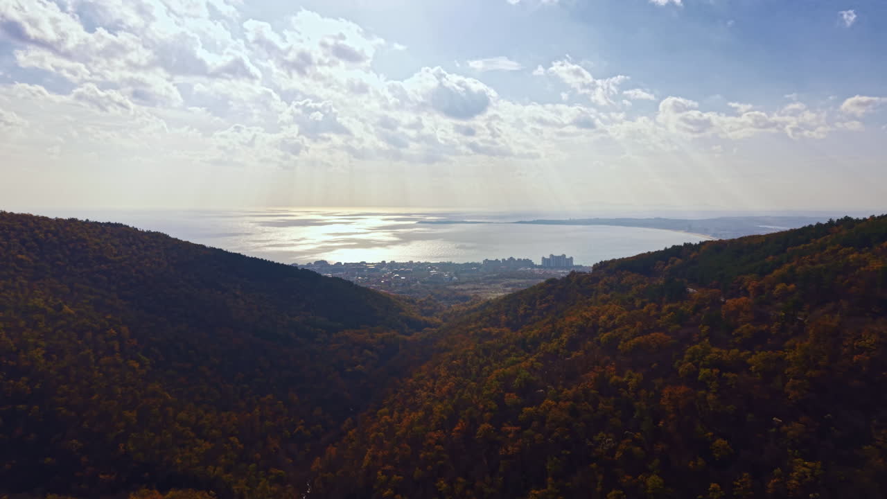 Majestic view of rolling hills and shimmering waters under a vibrant sky at golden hour in the heart of autumn's splendor