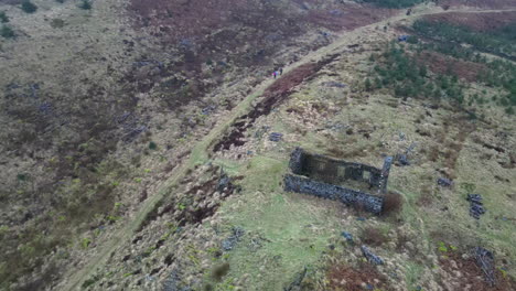 revelación aérea circular de la colina cubierta de árboles alrededor de dos casas abandonadas