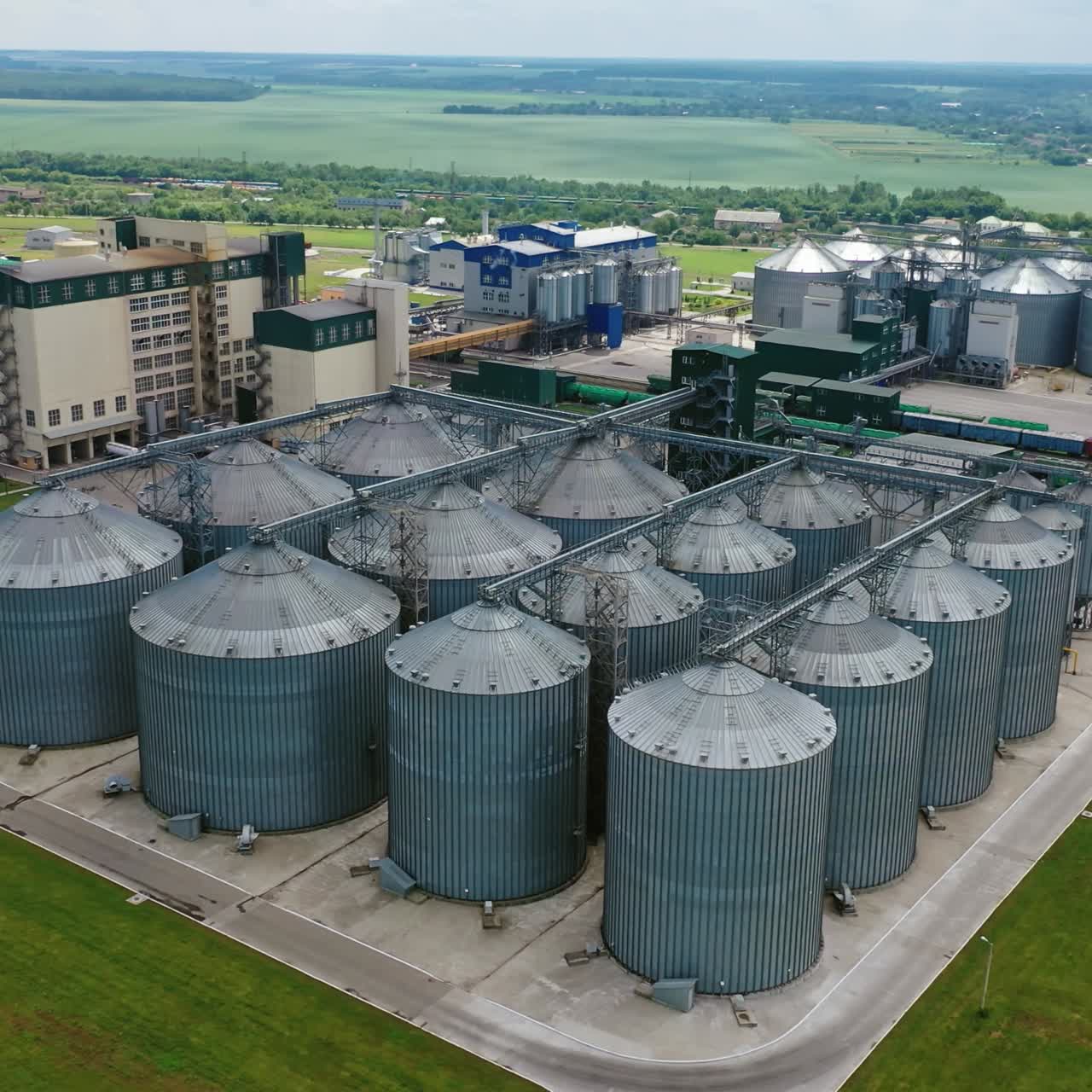 Agriculture storage for harvest. Grain elevators on green nature background. Exterior of agricultural factory. Aerial view.