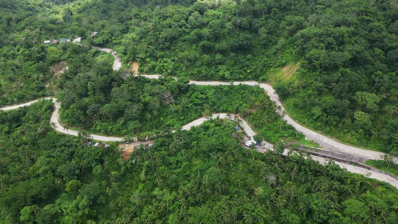 Aerial overview of mountainside winding road surrounded by lush tropical jungles in Catanduanes Island, Philippines.