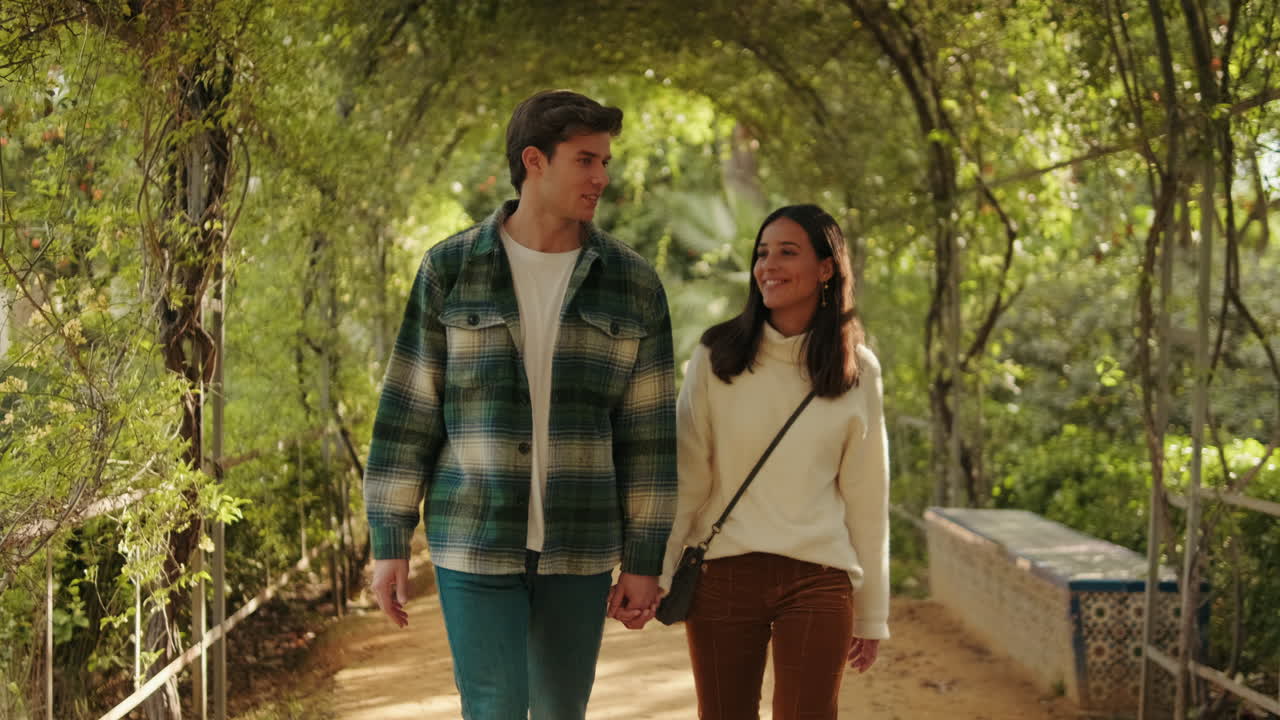 Happy young couple man and woman walking inside green arch