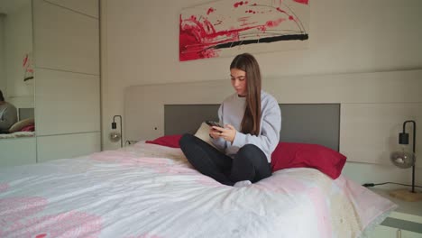 woman sitting on bed using phone