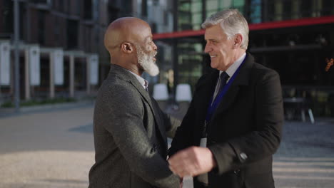 portrait of professional executive businessmen meeting shaking hands smiling happy in city