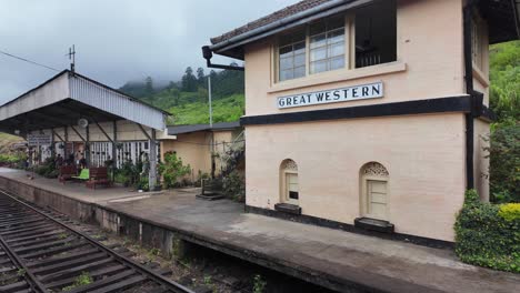 the great western station in talawakelle, sri lanka, showcases a charming blend of rustic architecture and natural beauty, with misty hills and an overcast sky creating a tranquil atmosphere.