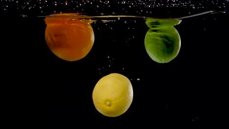 frutas cítricas coloridas que caen al agua en cámara lenta