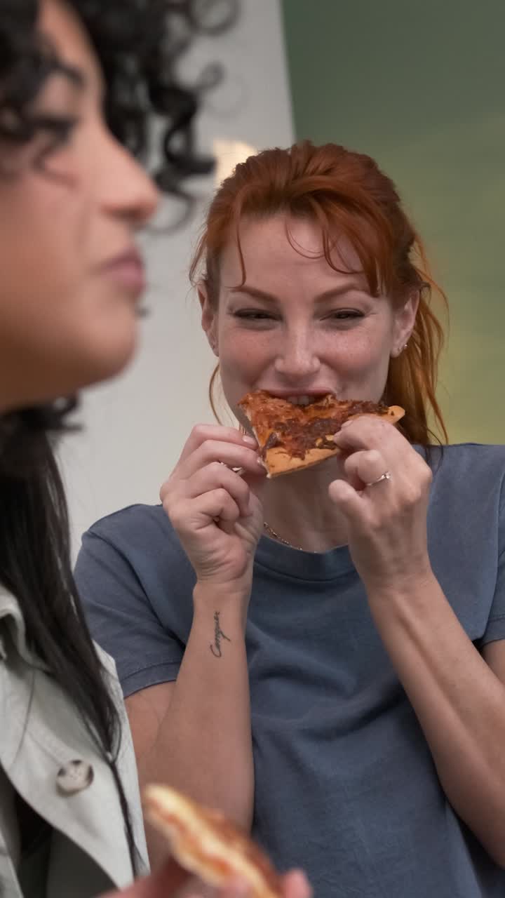 Beautiful woman eating pizza slice while enjoying weekend get together with friends