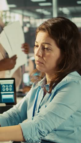 vertical video stressed worker in office sights, burdened by too many documents to review