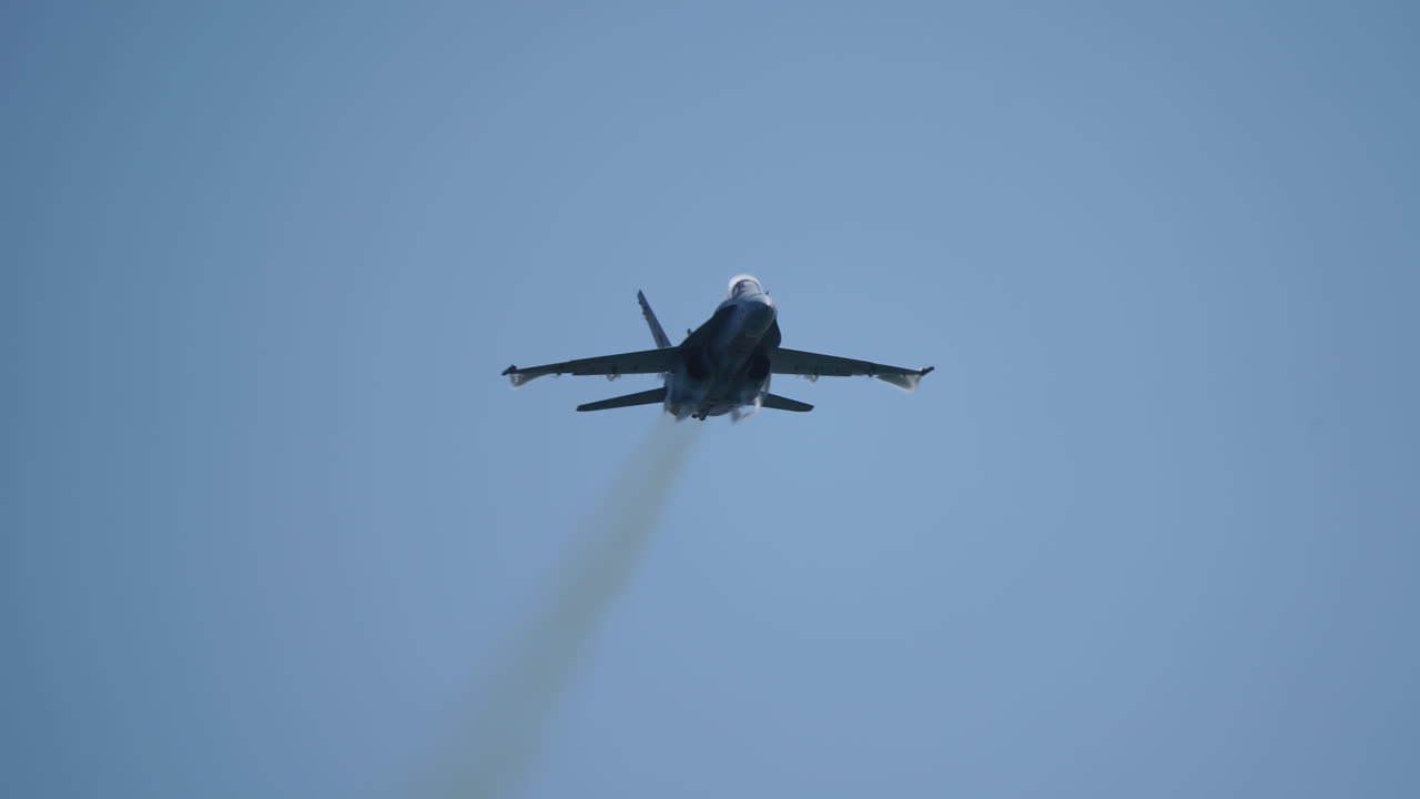 Military jet aircraft flying in slow motion with visible vapor cone from shockwave caused by pressure difference