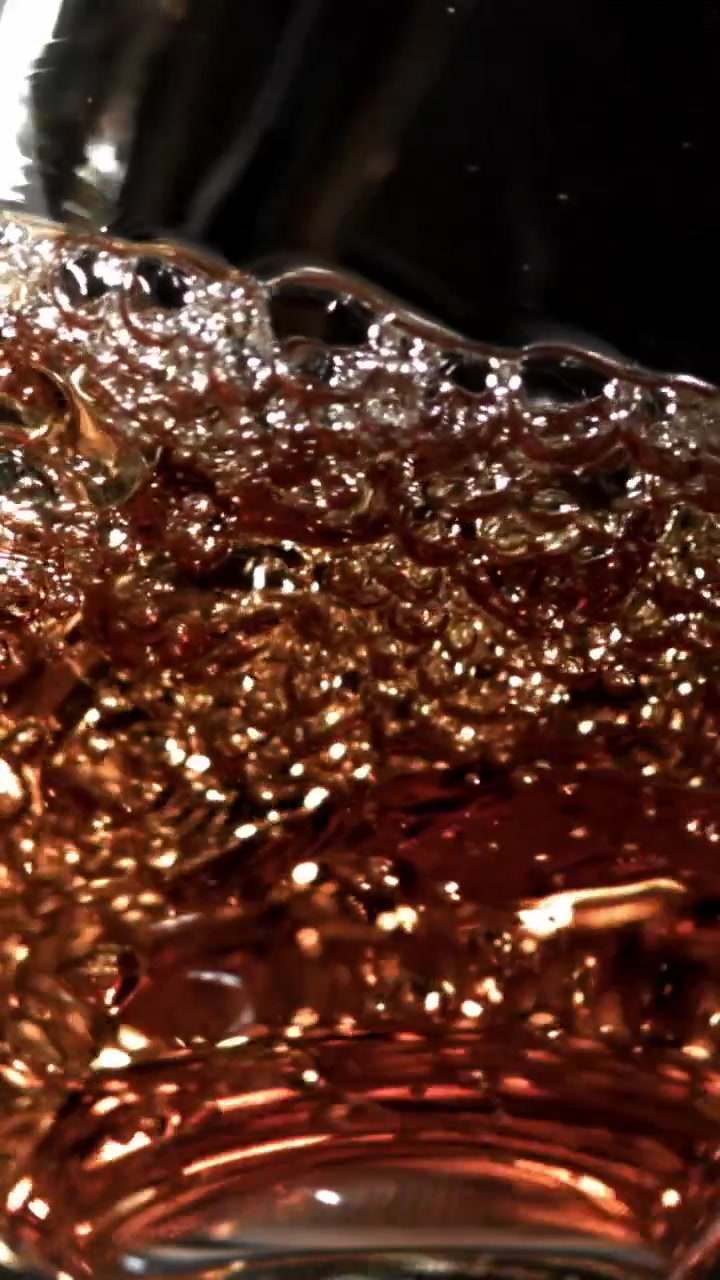Primo piano di liquido ambrato con bollicine scintillanti e movimento dinamico
