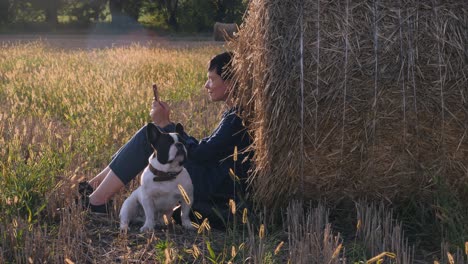 young woman sitting at the meadow with french bulldog