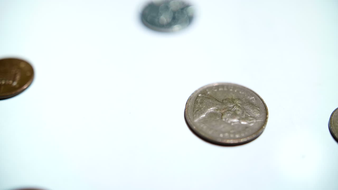 Pièces de monnaie tombant et rebondissant au ralenti sur une surface blanche
