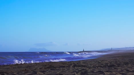 playa española vacía en un día ventoso, toma estática con gibraltar en el fondo