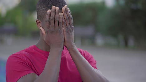 afro-american man suffering from headache in park, massaging head