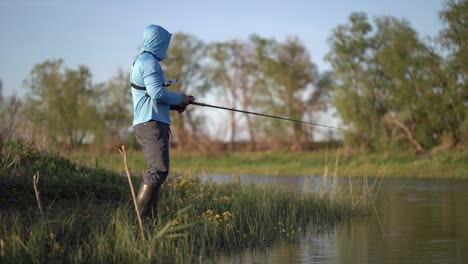 the fisherman sportsman catches a predatory fish on a spinning on the lake.