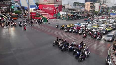 motorcycles and cars crossing a bustling city junction